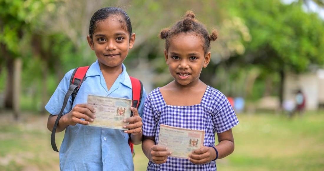 Siblings Sam and Caroline Adikakua, holds their vaccination passports in front of the Nacula Nursing Station, Yasawa Islands, Fiji.